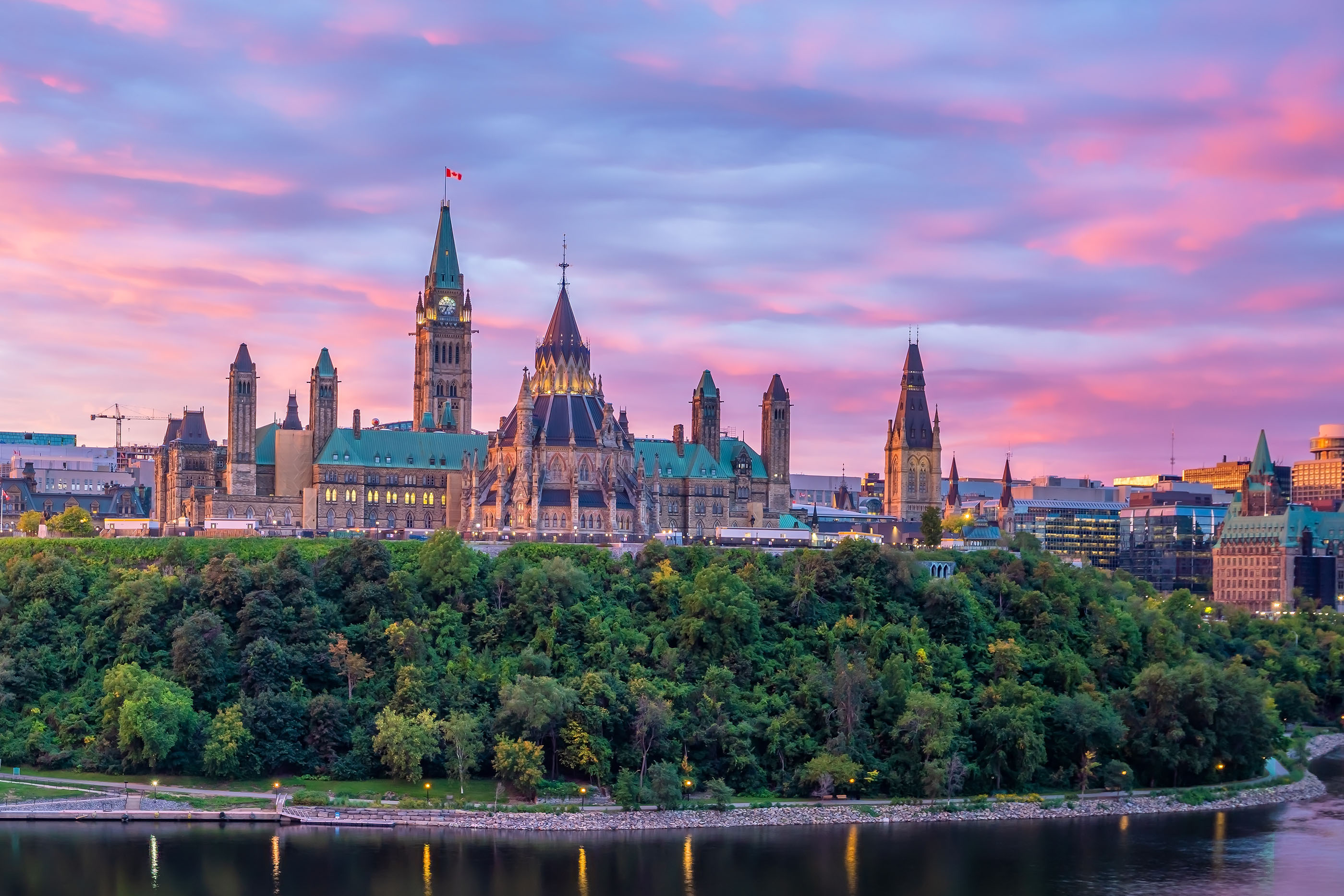 The parliament buildings in Ottawa are backlit by a beautiful sunset.