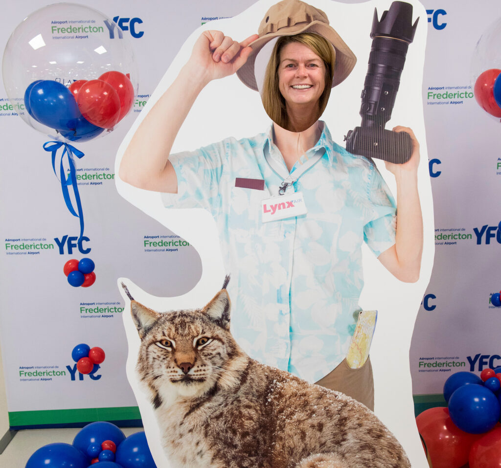 A woman looks through a selfie station that makes it appear as if she is standing next to a lynx.