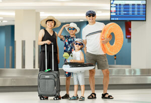 Mother, father, 2 children, travelling with luggage and beach gear.