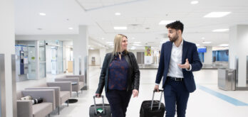 Two travellers walk with their luggage in the Fredericton International Airport